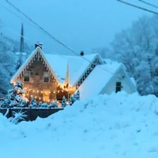 House with large snow bank and Christmas lights