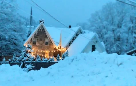 House with large snow bank and Christmas lights